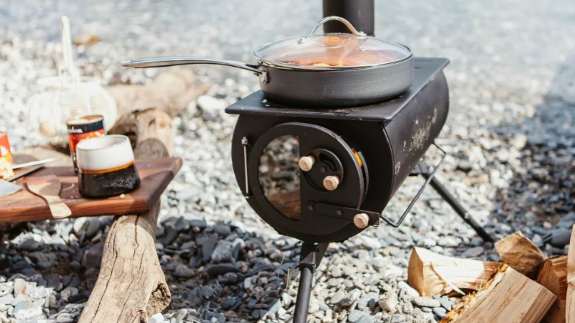 Anevay Frontier Plus Portable Wood Burning Stove - set up on a pebble beach with food cooking on top
